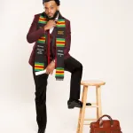 Herzing graduate posing with one foot on a stool in his cap and sash.