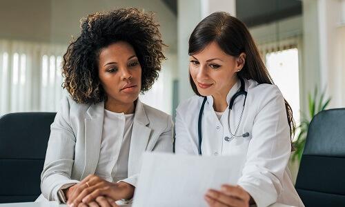 Nurse administrator reviewing patient data with physician