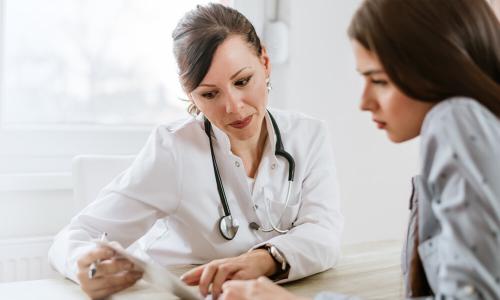 Women's health nurse practitioner referencing test results with patient