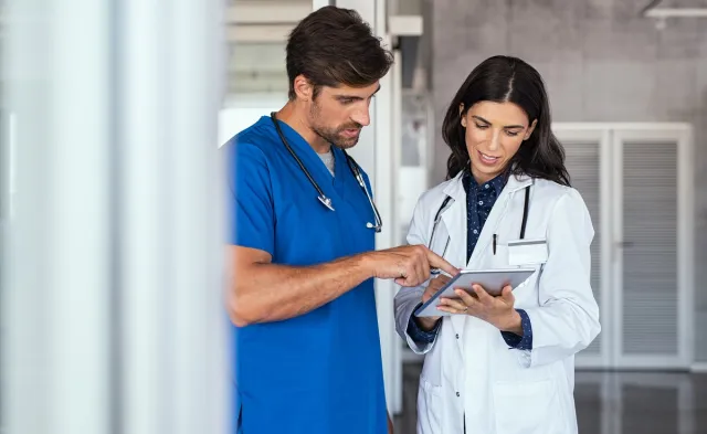Nurse teacher reviewing patient charts with nursing student in blue scrubs