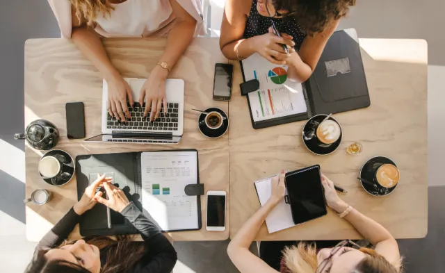 Top view of group of students sitting together at table. University students doing group study.