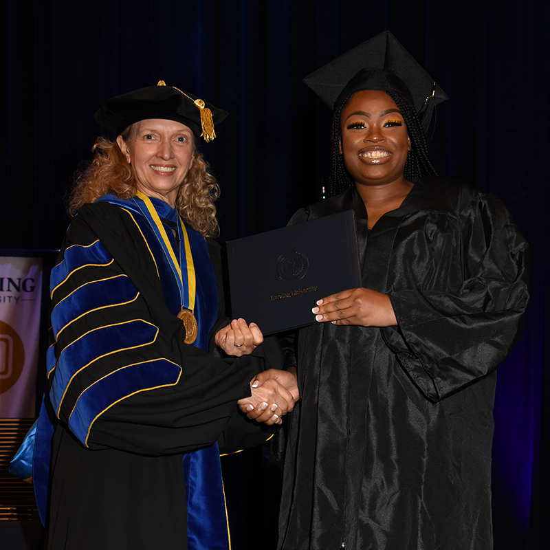 Herzing graduat receives her diploma from Renee Herzing.