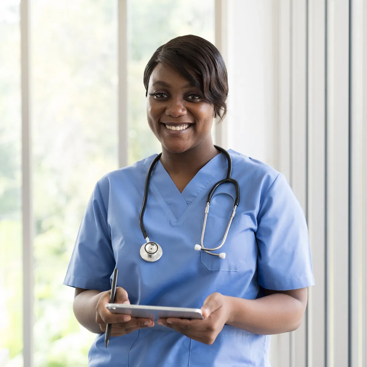 Herzing University medical assisting student smiling confidently with a stethoscope and tablet in hand, symbolizing readiness for healthcare careers.