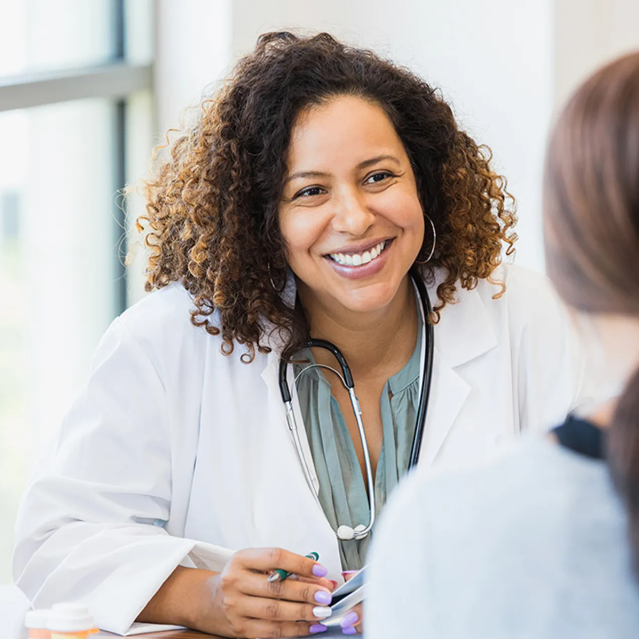 Women's health nurse practitioner smiling while speaking with female patient