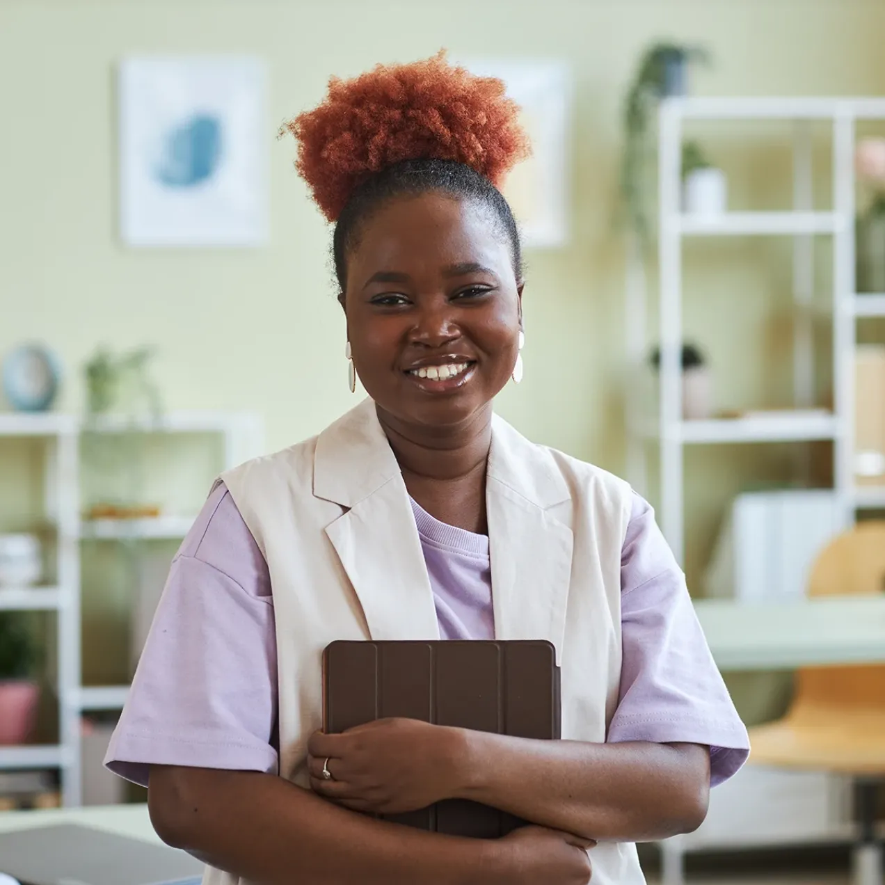 Smiling student holding a tablet in a classroom setting, preparing for a career in health and human services.