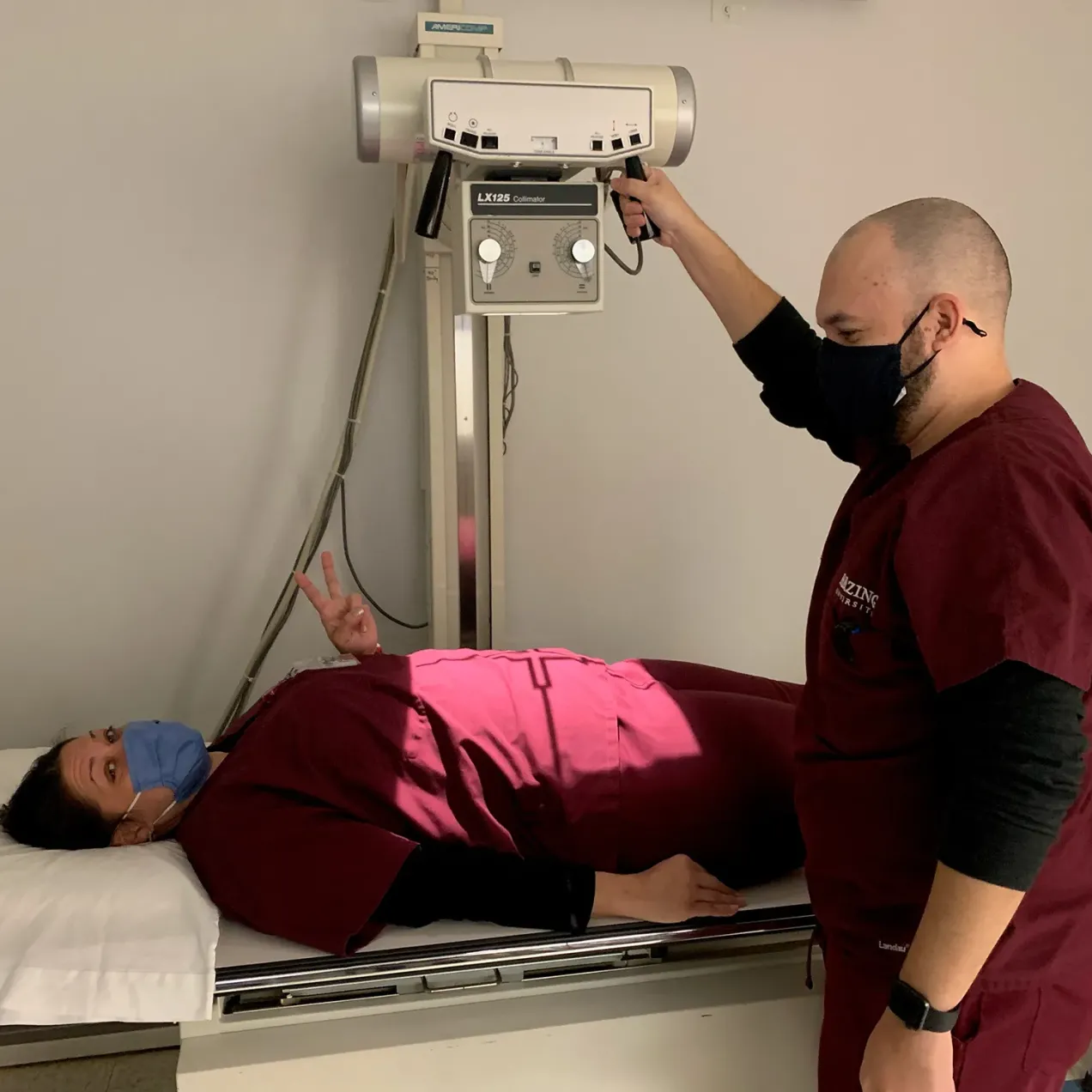 Herzing University Radiologic Technology students in scrubs participating in laboratory simulation on x-ray machine.