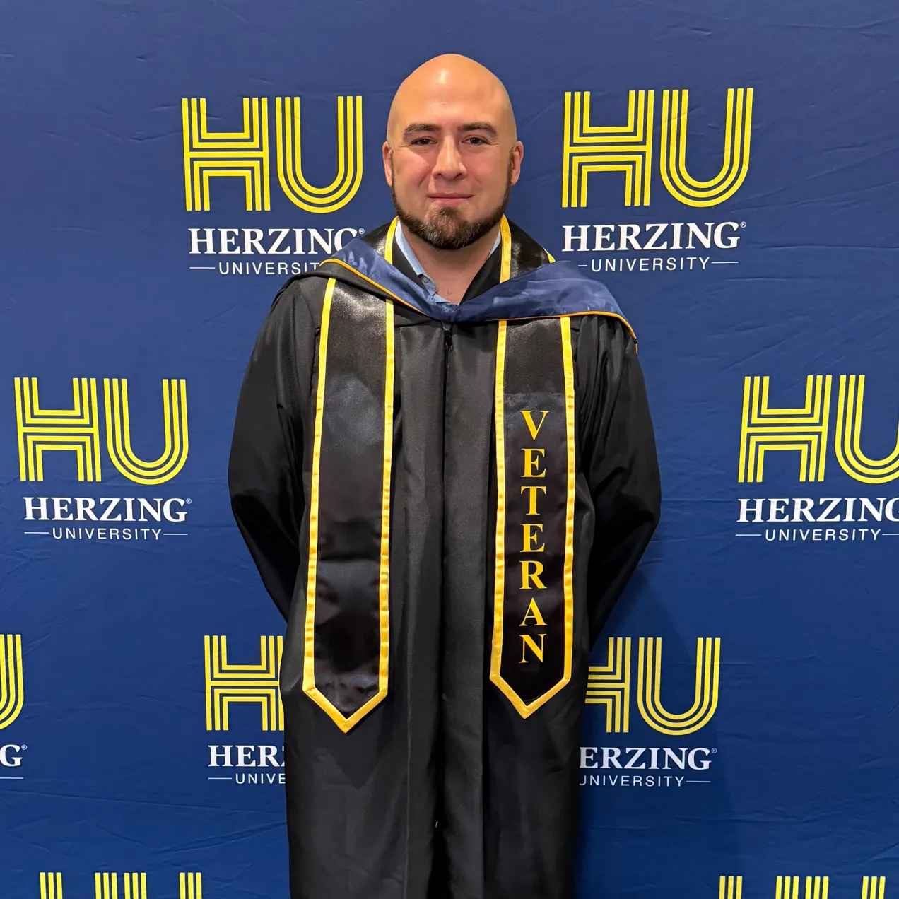 Herzing University veteran graduate in cap and gown at commencement ceremony, celebrating military student success