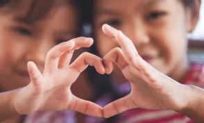 Two cute asian child girls making heart shape with hands together