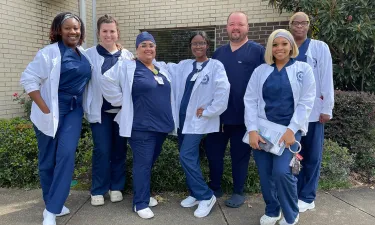 Seven Herzing University MSN Direct Entry nursing students in scrubs smiling while posing for photo