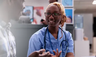 Illinois medical assistant smiling and discussing treatment with patient in clinic