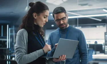 Team of cybersecurity professionals reviewing security implementation on laptop