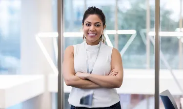 Confident healthcare administrator standing in a modern office environment with arms crossed, demonstrating leadership and professionalism.