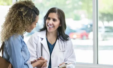 Women's health nurse practitioner smiling with patient during appointment