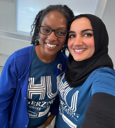 Two Herzing University students smiling and wearing Herzing University branded shirts, showcasing camaraderie and school spirit.