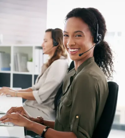 Professional woman wearing a headset, seated at a desk in a modern office, representing careers in medical coding and administrative roles.