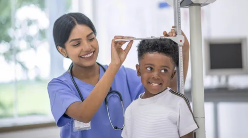 Medical assistant checking the height of pediatric patient