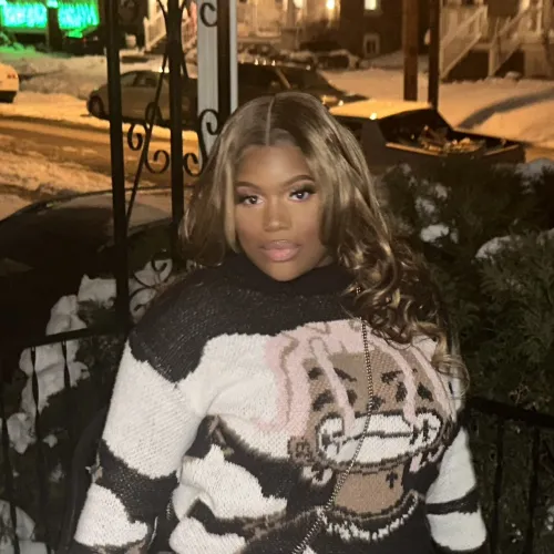 Woman in a colorful sweater posing on front porch in the winter surrounded by snow