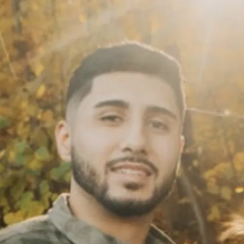 Man poses for a selfie in bright sunshine and fall foliage