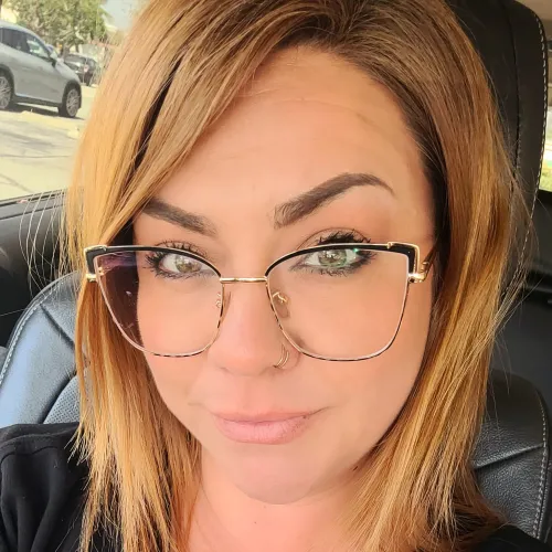 Woman in glasses poses for a selfie in a car