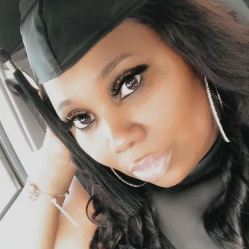 African American woman in a grad cap sits in a car poses for a selfie