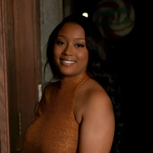 African American woman in a rust dress poses in a doorway