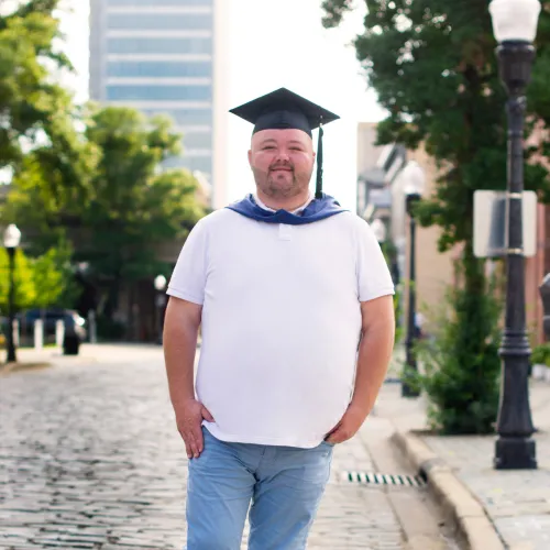 Christopher Green standing in the middle of the street in a grad cap