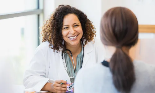 Women's health nurse practitioner smiling while speaking with female patient