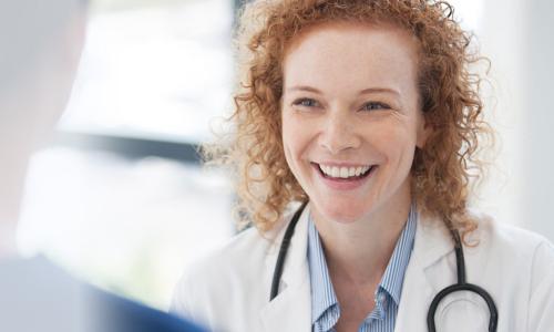 Women's health nurse practitioner smiling with patient during appointment 