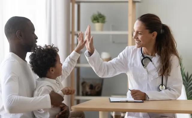 Family nurse practitioner high fiving pediatric patient in office during appointment