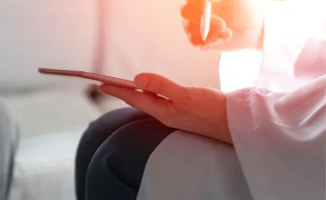 PMHNP holding tablet during patient appointment taking notes