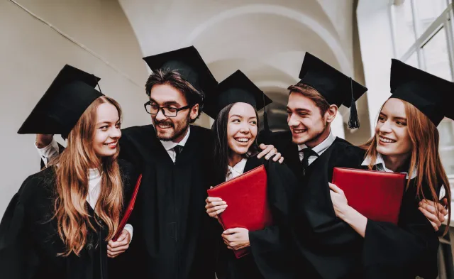 Five college graduates holding diplomas celebrating on graduation day