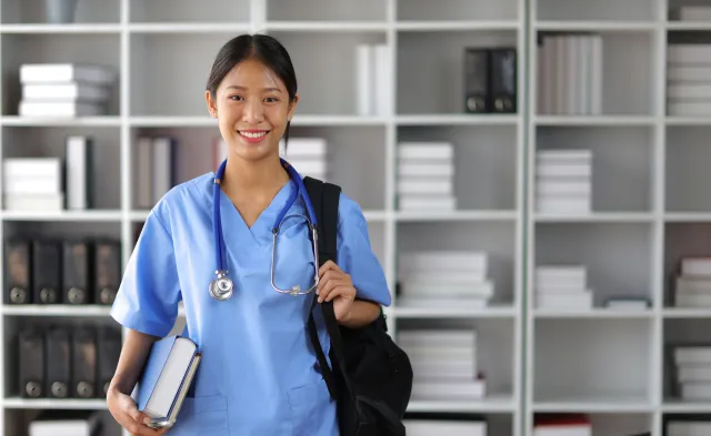 Nursing student smiling in library with bag over shoulder