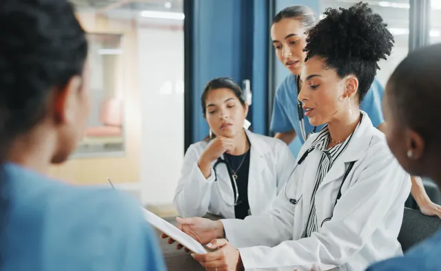 Healthcare manager in white coat leading team discussion in hospital conference room