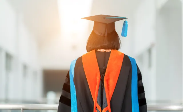 PhD student with their back facing viewer wearing an orange nursing hood