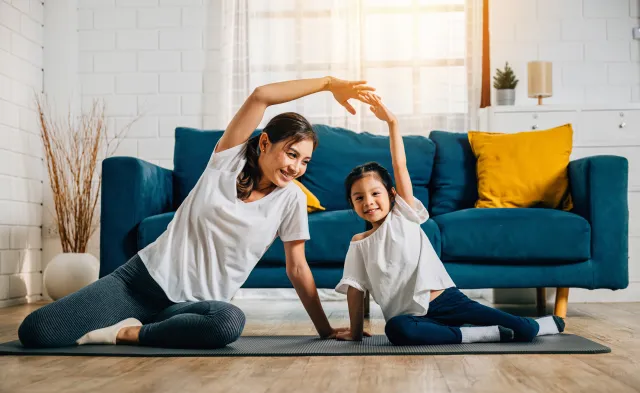 A mother coaches her little daughter in yoga creating a family bond filled with happiness relaxation and togetherness.