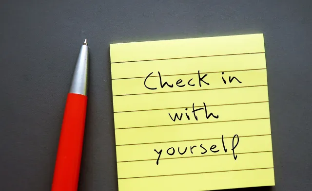 Note paper on gray background with handwritten text - Check in with yourself - carving out time each day to ask yourself how you're doing