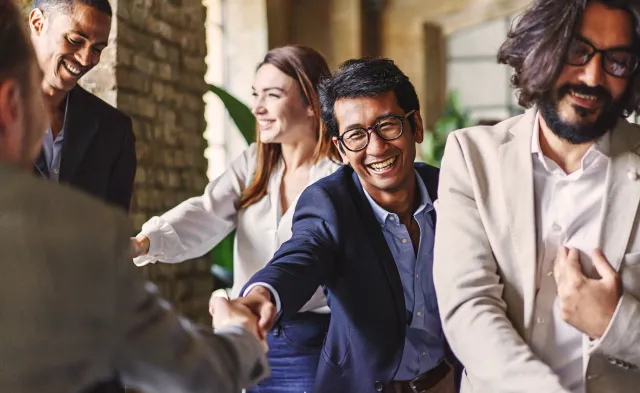 Group of diverse professionals celebrating with a handshake at a corporate event, embodying teamwork and achievement.