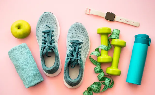 Healthy lifestyle and fitness concept. Sneakers, dumbbells, towel, green apple and fitness bracelet.