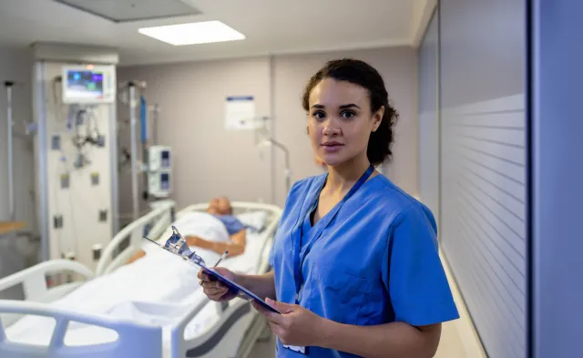 Portrait of a Latin American nurse working at the ICU and checking on a patient - healthcare and medicine concepts