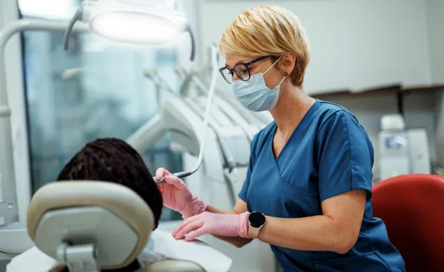Professional female dentist performing dental treatment on a female patient, demonstrating precision, care, and a supportive healthcare environment.
