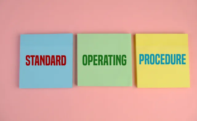 Business Acronym SOP as Standard Operating Procedure. pink background. text on yellow, blue and green paper