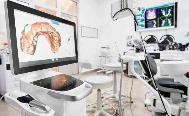 Interior of dental office with modern equipment and dental intraoral scanner with teeth on display, medical system for intraoral scanning. Concept of digital dentistry and dental scanning technology.