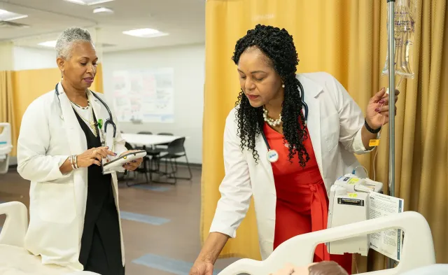 Nursing student in labs with instructor training on test mannequin