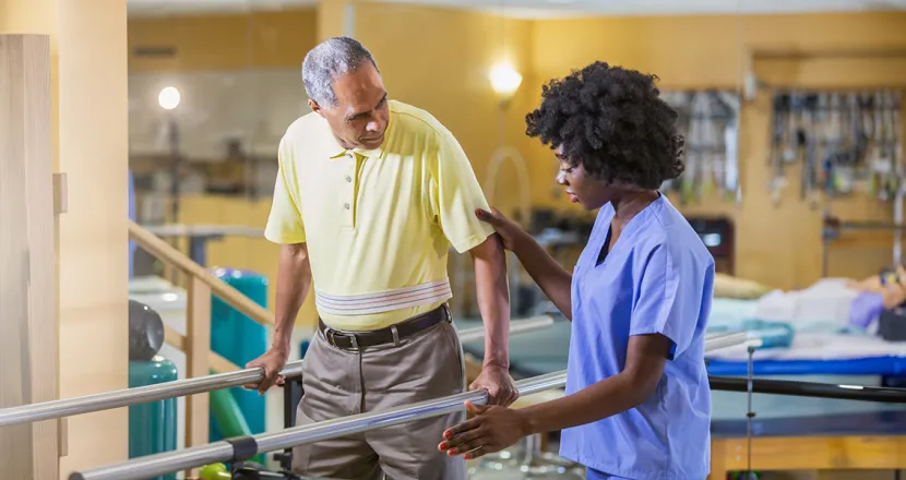 Physical therapist assistant helping patient regain balance while walking