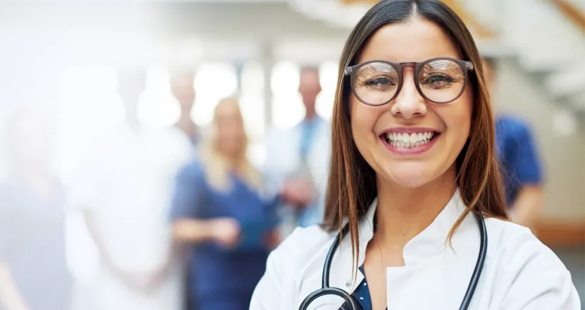 Family nurse practitioner with DNP smiling with medical team in background