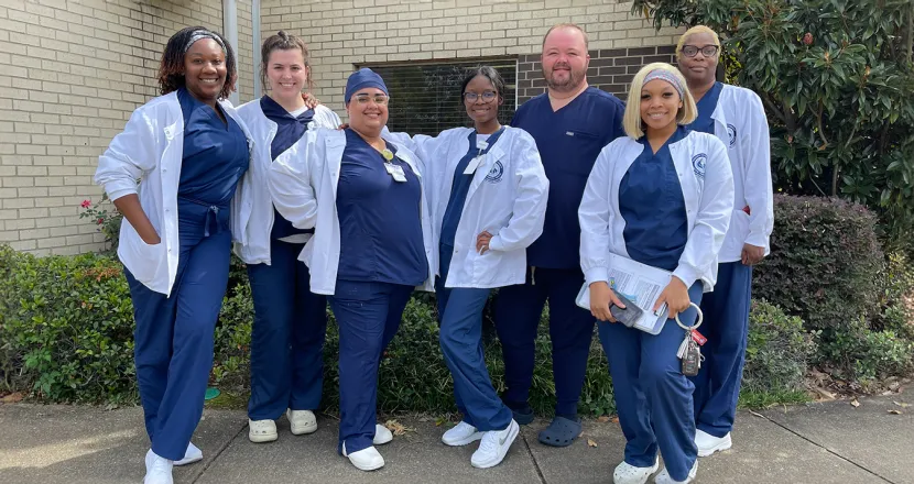 Group of Hering MSN students in white coats standing outdoors.