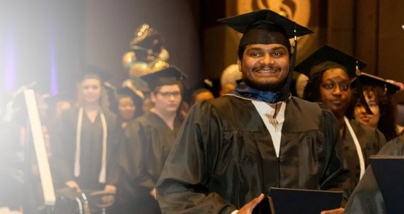 Herzing University online MBA graduate smiling while walking to receive his degree