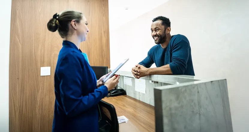 Medical office professional assisting a patient at the reception desk, illustrating a potential career in the Medical Office Administration program.