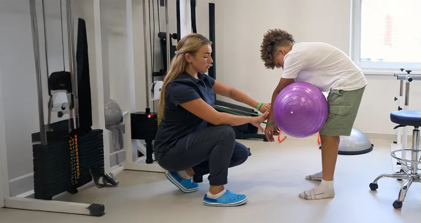 A physical therapist assistant working with a child in a rehabilitation setting, demonstrating hands-on training in Herzing University’s Physical Therapist Assistant program.