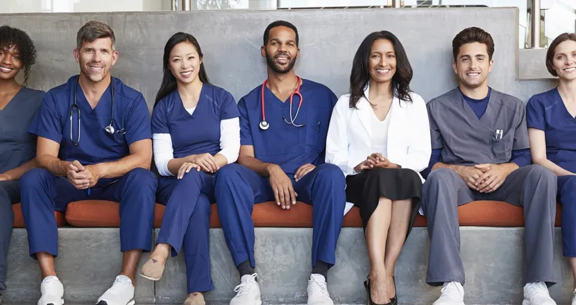 Diverse group of health sciences professionals and students sitting together on a bench in a modern setting, showcasing teamwork and collaboration in healthcare.
